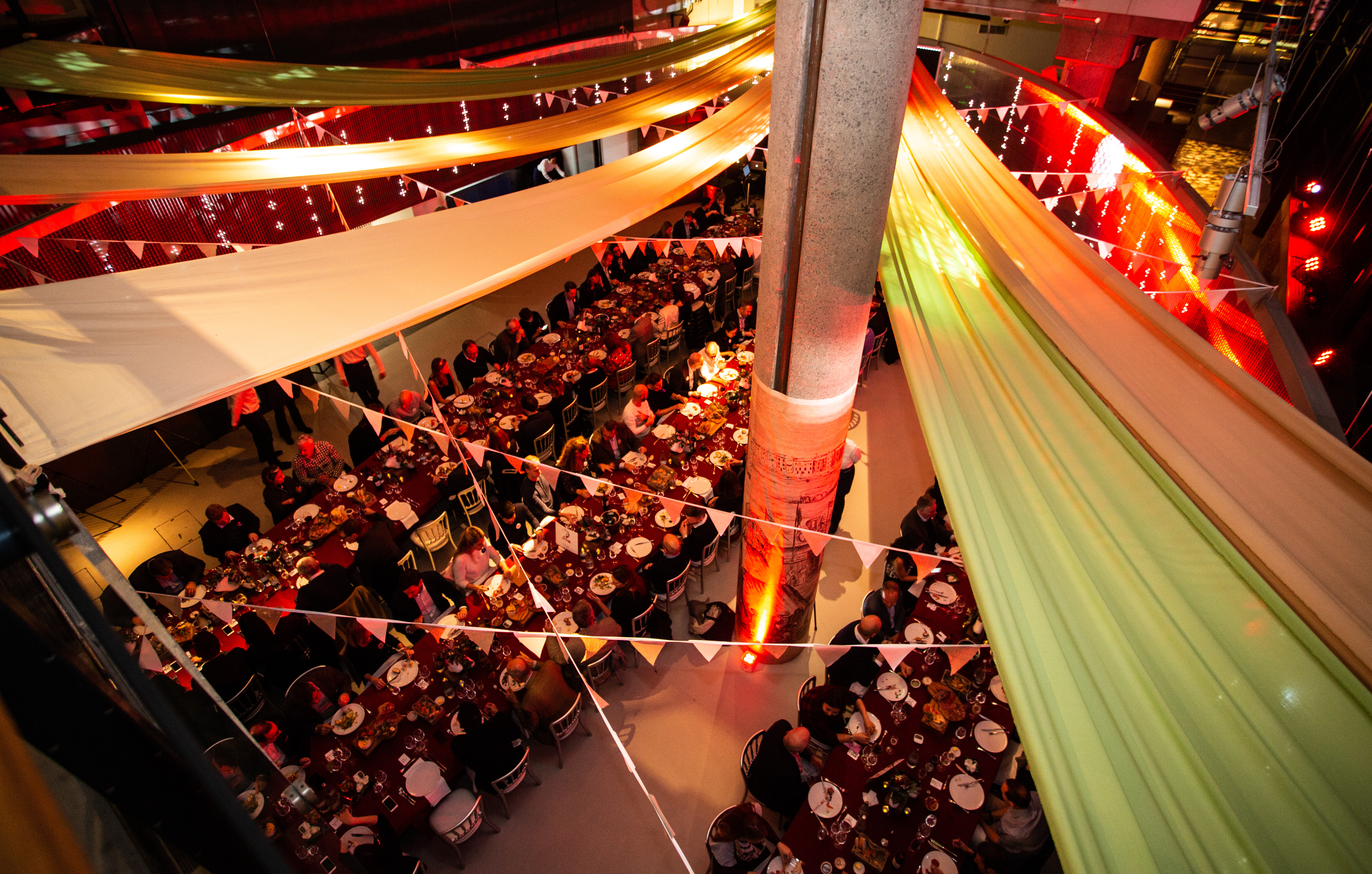 Vibrant banquet event space in London Museum with elegant tables and colorful drapery.