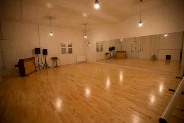 Versatile event space with polished wooden floors and large mirror for workshops and dance classes.