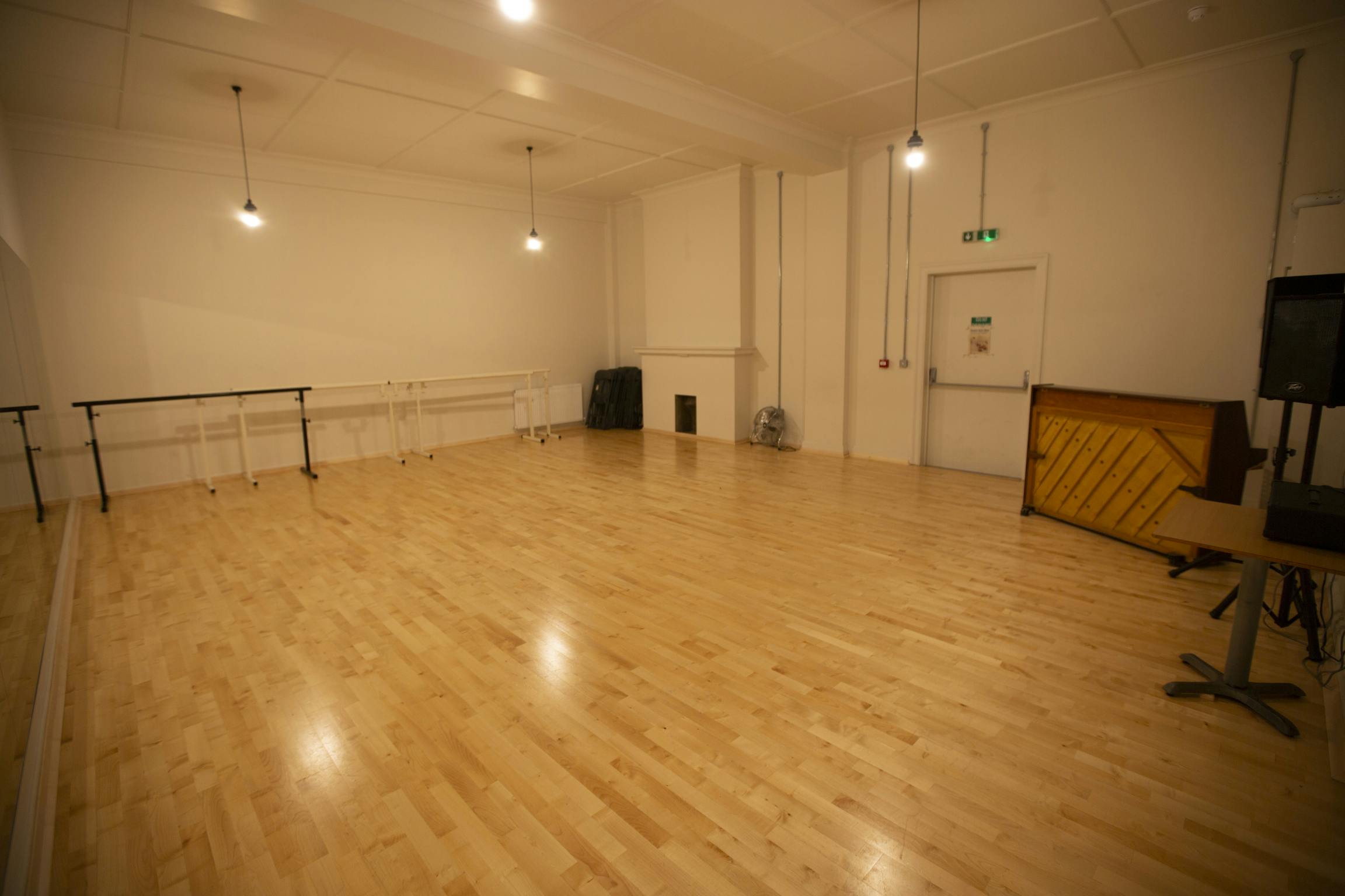 Versatile event space with wooden floors and piano for workshops and dance classes.