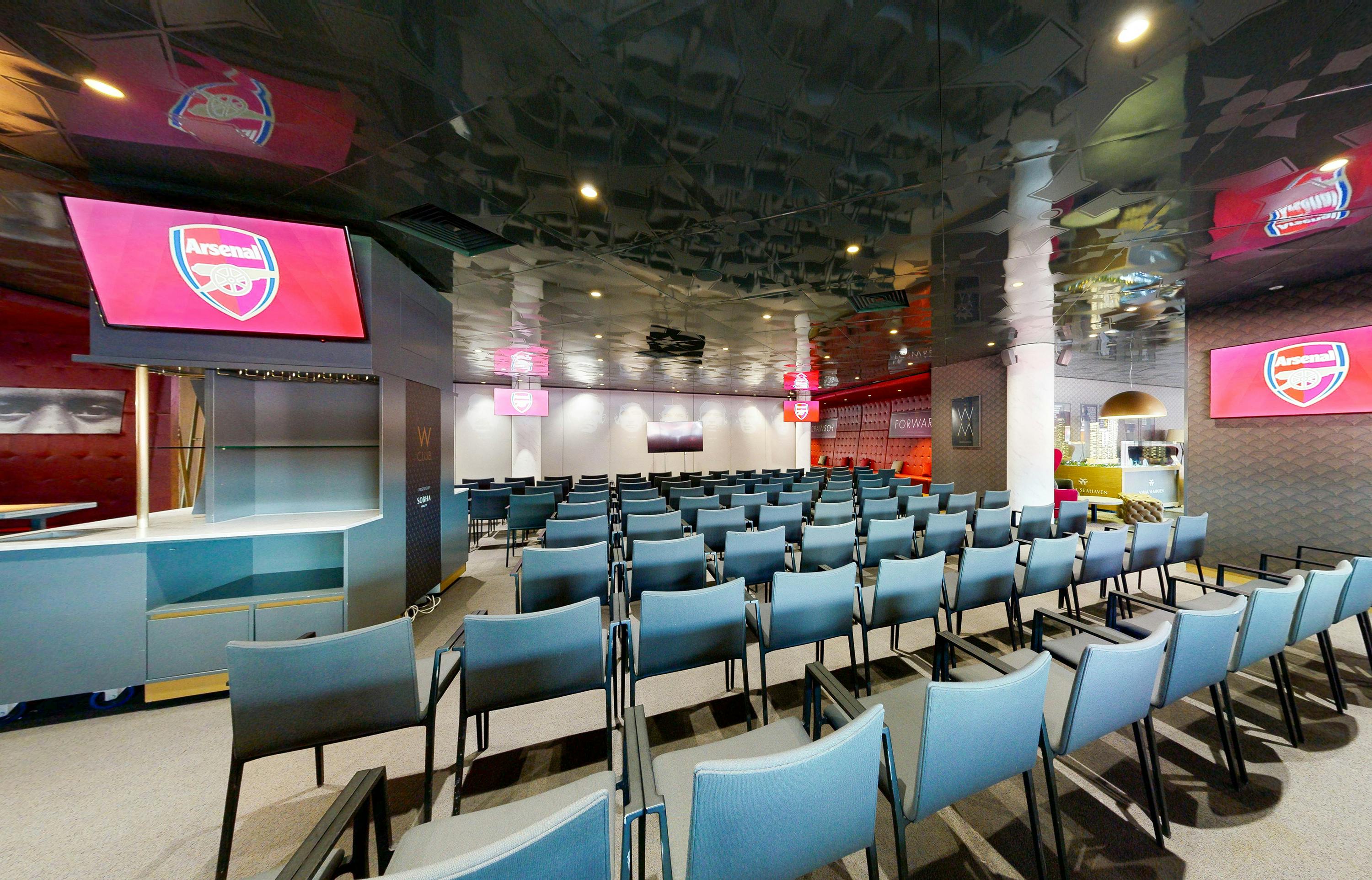 Modern event space at Arsenal's Emirates Stadium with blue chairs for corporate meetings.