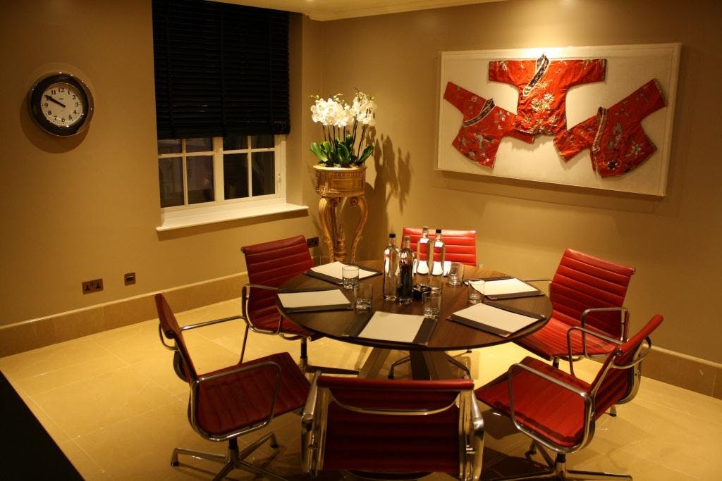 Private Suite 6 at The May Fair Hotel, modern meeting room with round table and red chairs.