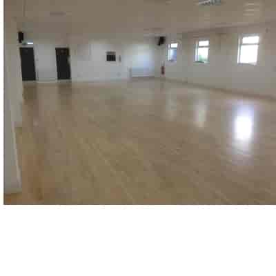 Spacious event space with polished wooden floors, ideal for meetings and workshops.