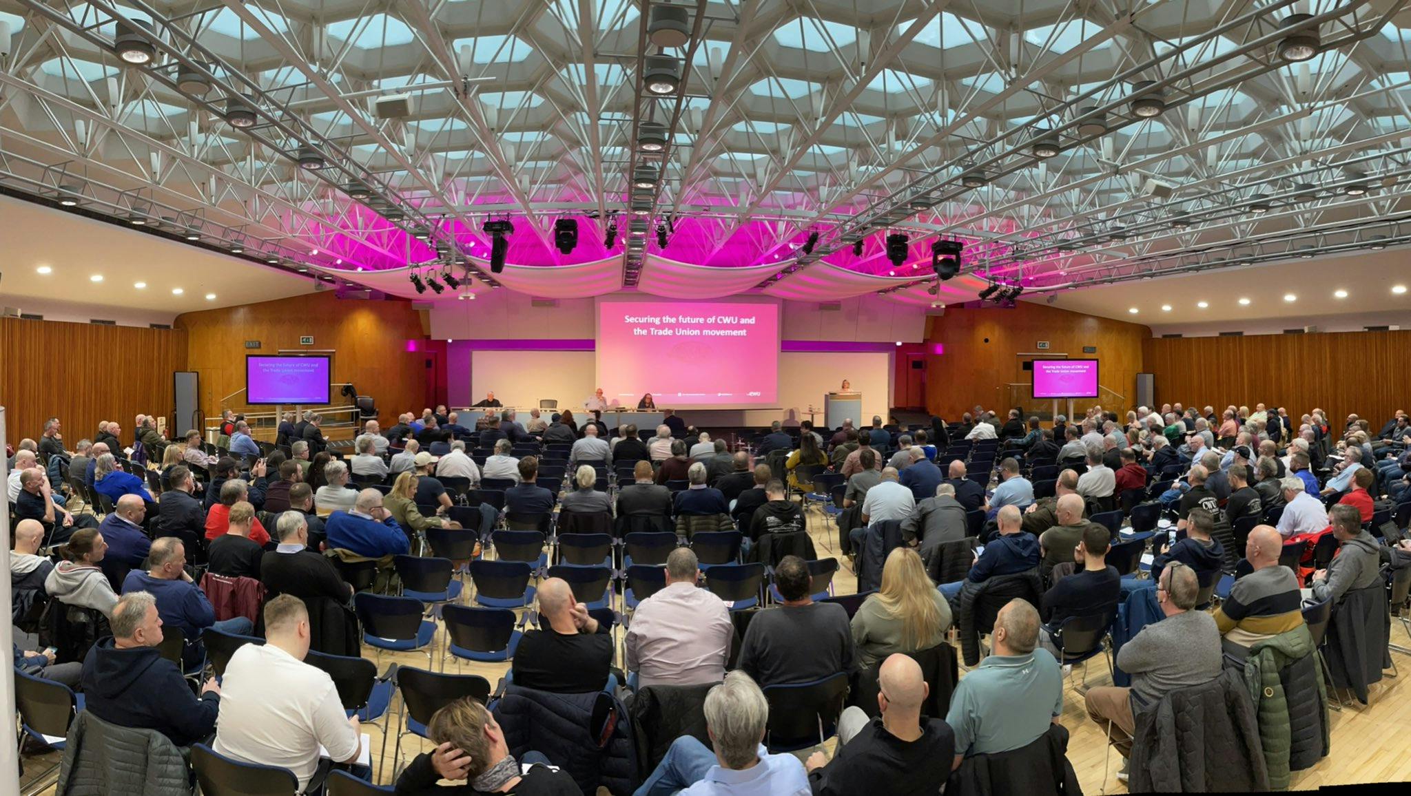 Congress Hall conference with engaging speaker, modern AV tech, and vibrant pink lighting.