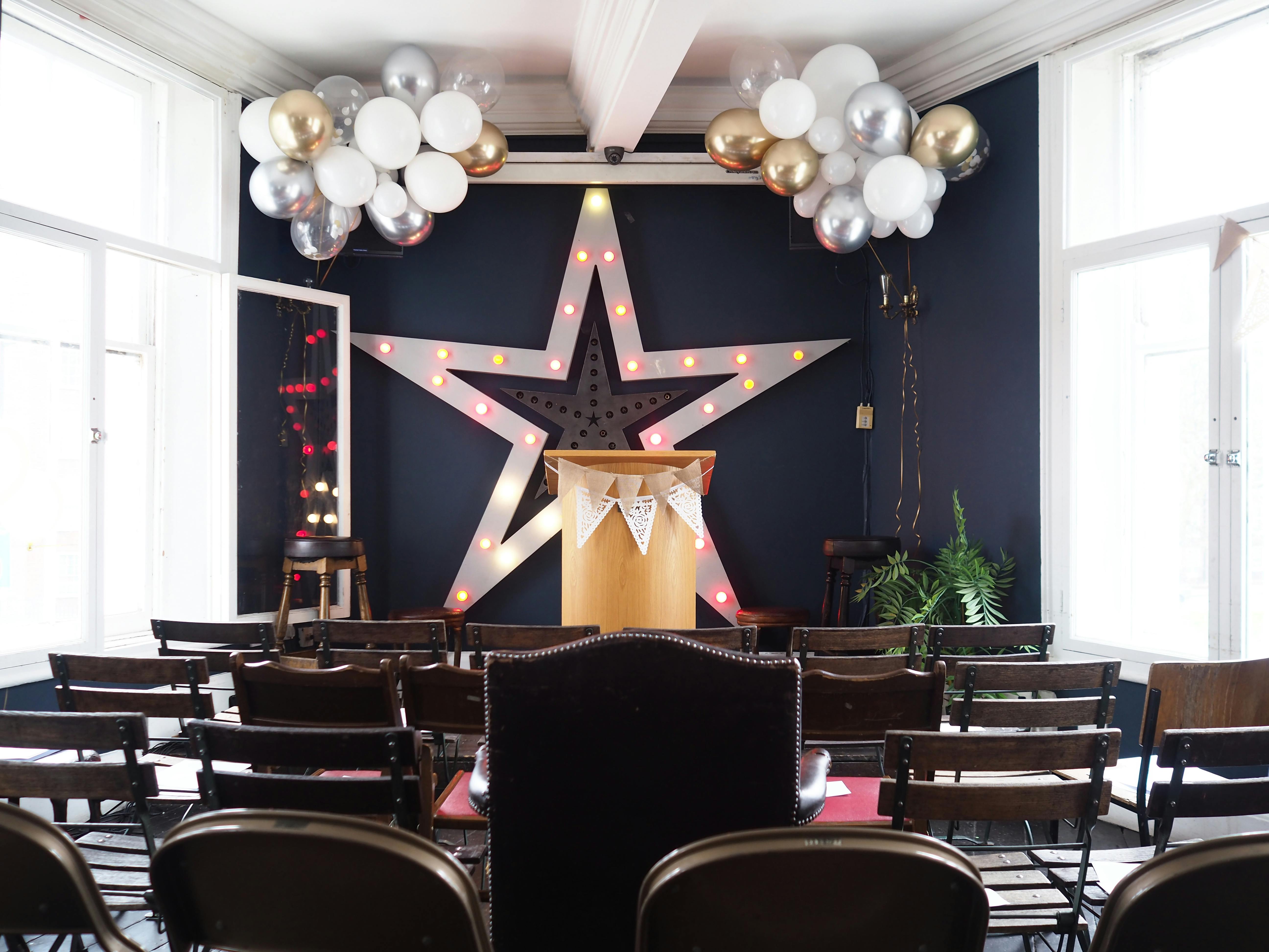 Event space at The Big Top, Hackney Downs, with star backdrop and festive balloons.