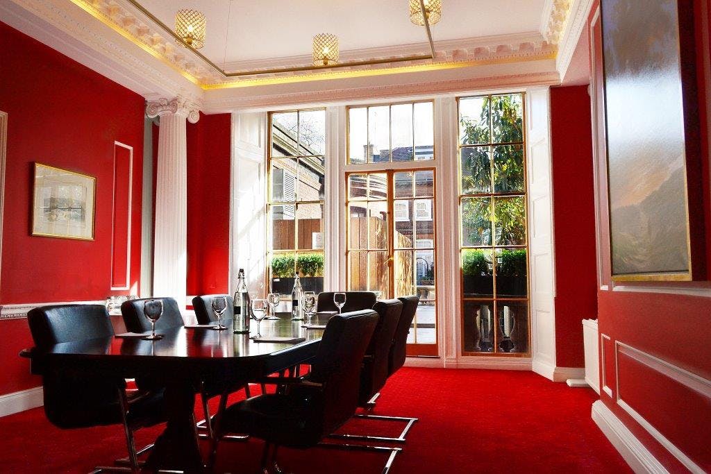 Stylish Ruby Salon meeting room with black table, red walls for productive events.