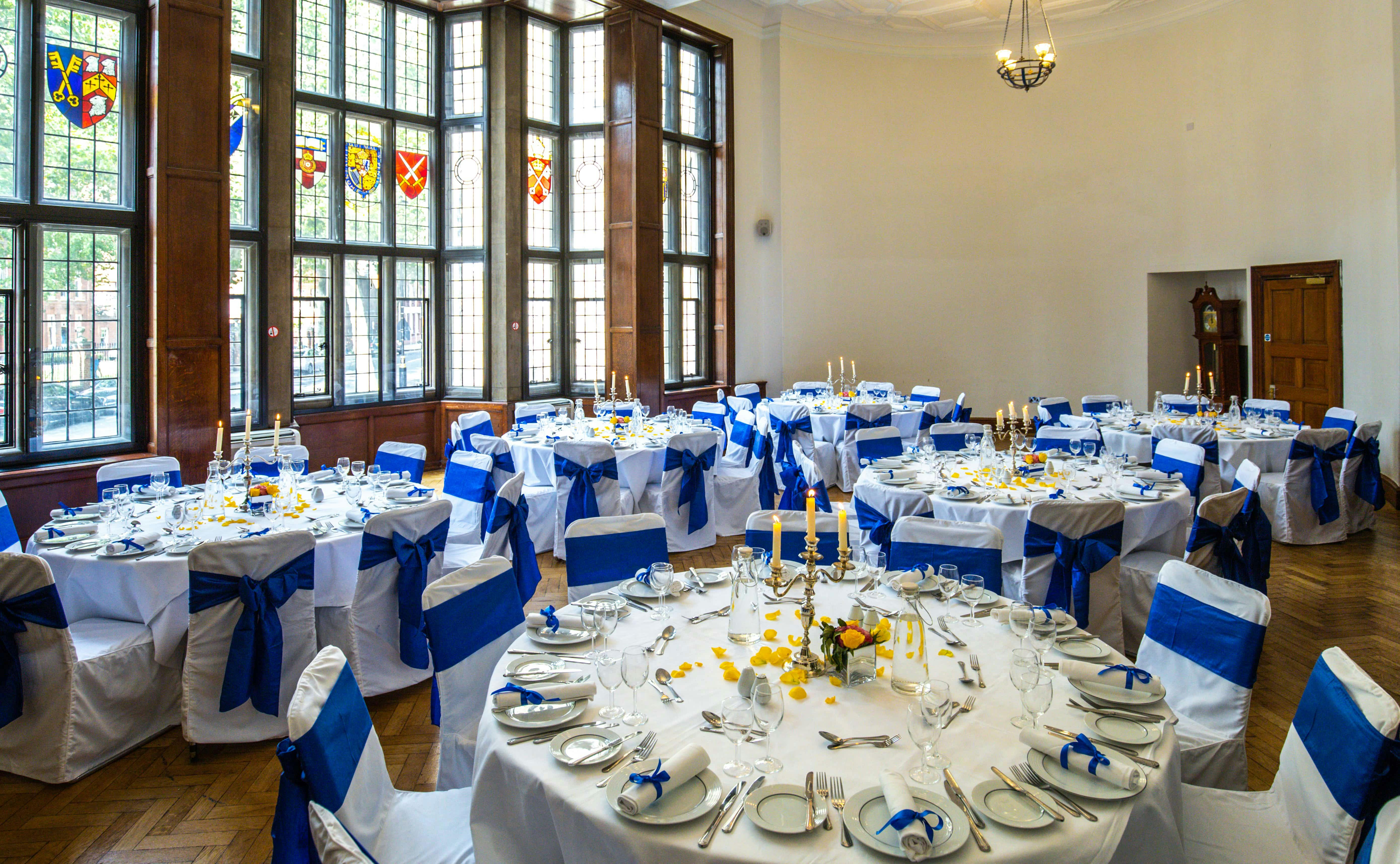 Elegant banquet hall with white linens and blue sashes for weddings and corporate events.