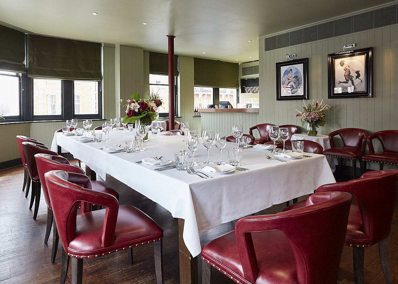 Private dining room with elegant table and plush red chairs for corporate events.