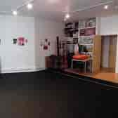 Versatile rehearsal space with black floor, ideal for workshops and small gatherings.