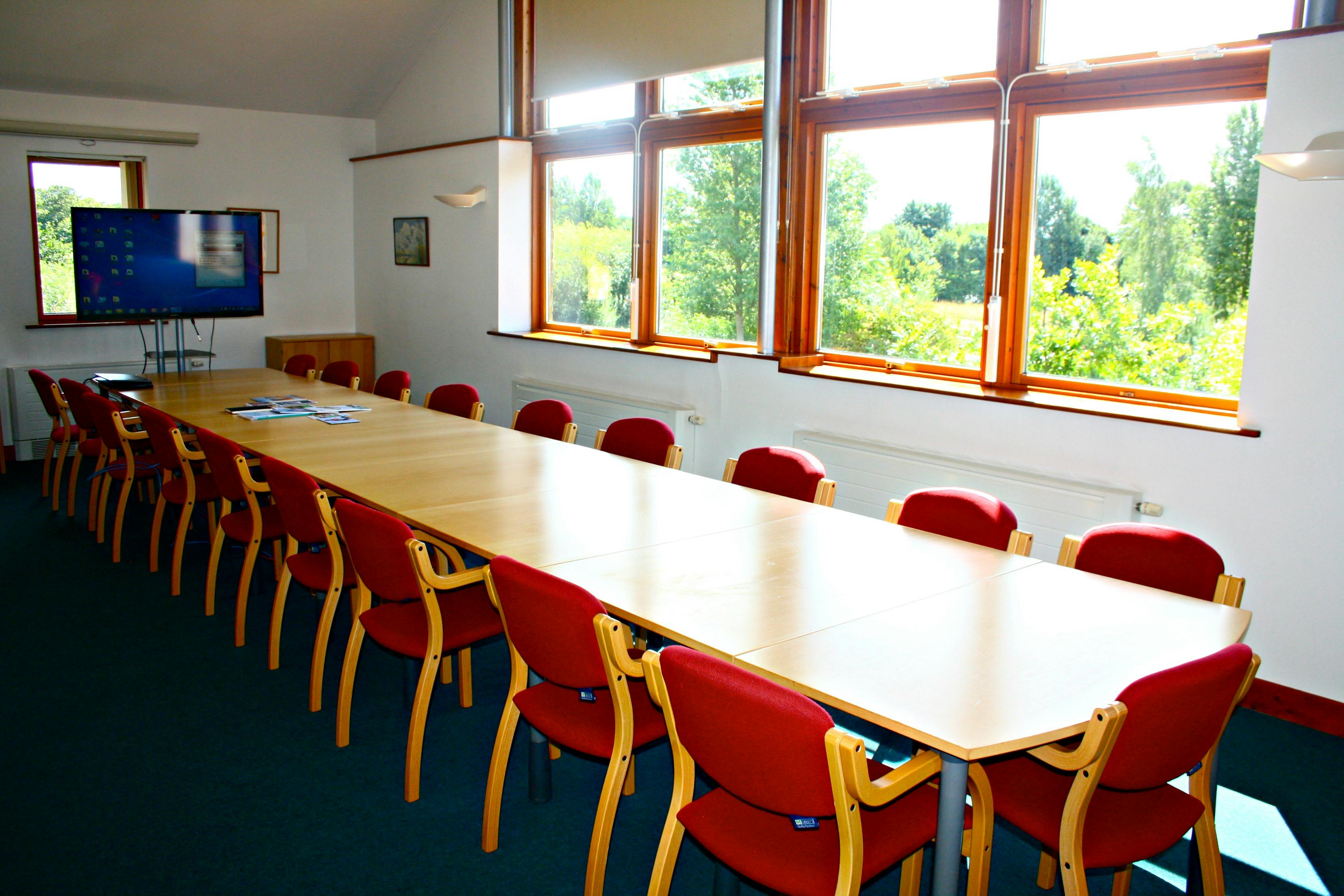 Spacious meeting room with red chairs, ideal for workshops at WWT London Wetland Centre.