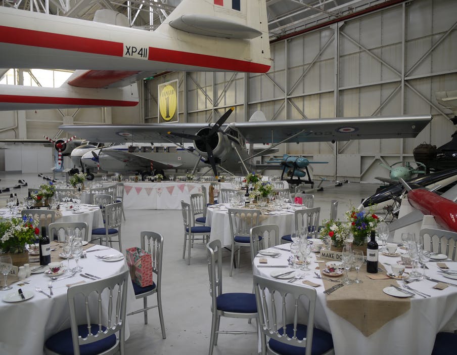 "Hangar One at RAF Museum: elegant event space with vintage aircraft and fine dining setup."