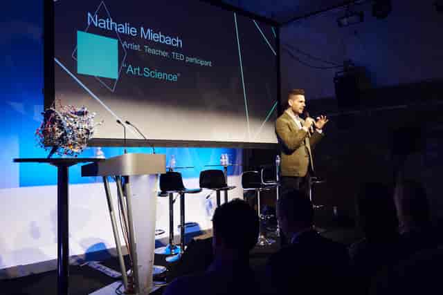 Dynamic speaker engaging audience at Shoreditch Studios event with modern stage setup.