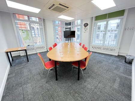 Bright meeting room with oval table and red chairs for collaborative sessions in Birmingham.