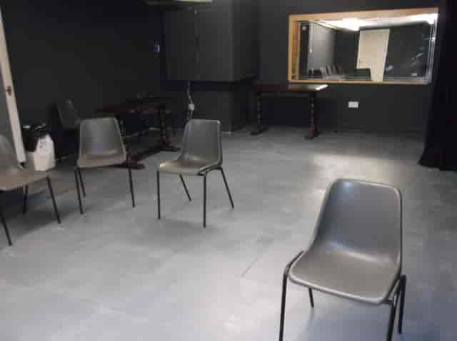 Minimalist meeting space with gray chairs for workshops and discussions at Calder Theatre.