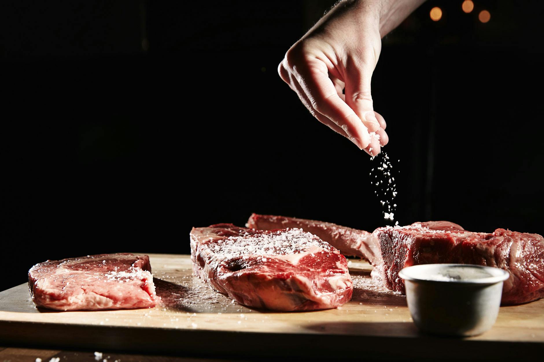 Hand sprinkling salt on gourmet meats at Exclusive Restaurant Hire event.