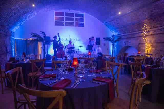Elegant event space with round tables, deep red napkins, and live band for upscale gatherings.