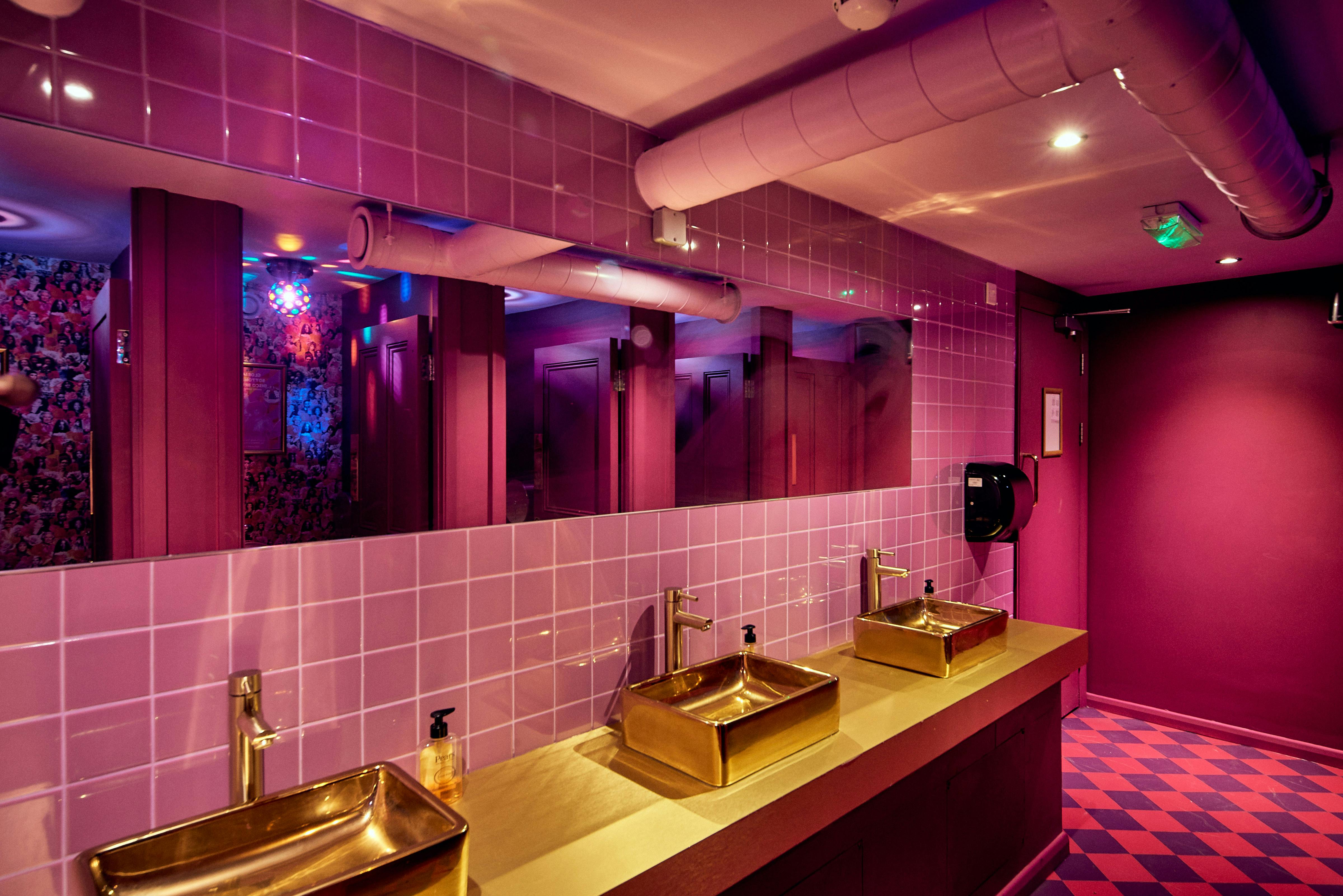 Vibrant restroom with gold sinks and purple tiles at Blame Gloria Clapham Junction event venue.