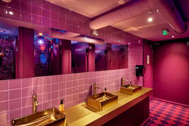 Vibrant restroom with gold sinks and purple tiles at Blame Gloria Clapham Junction event venue.