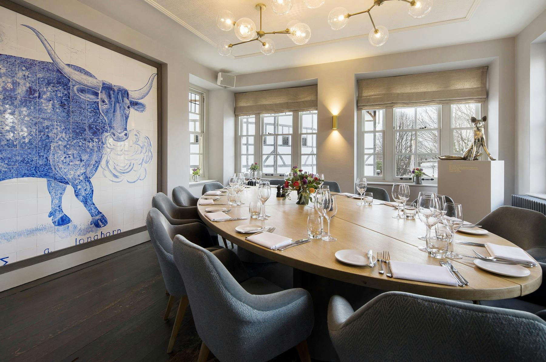 Stylish meeting room with round table and blue bull artwork for upscale events.