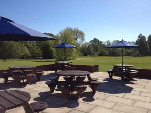 Outdoor meeting space at Reading University with picnic tables and blue umbrellas.