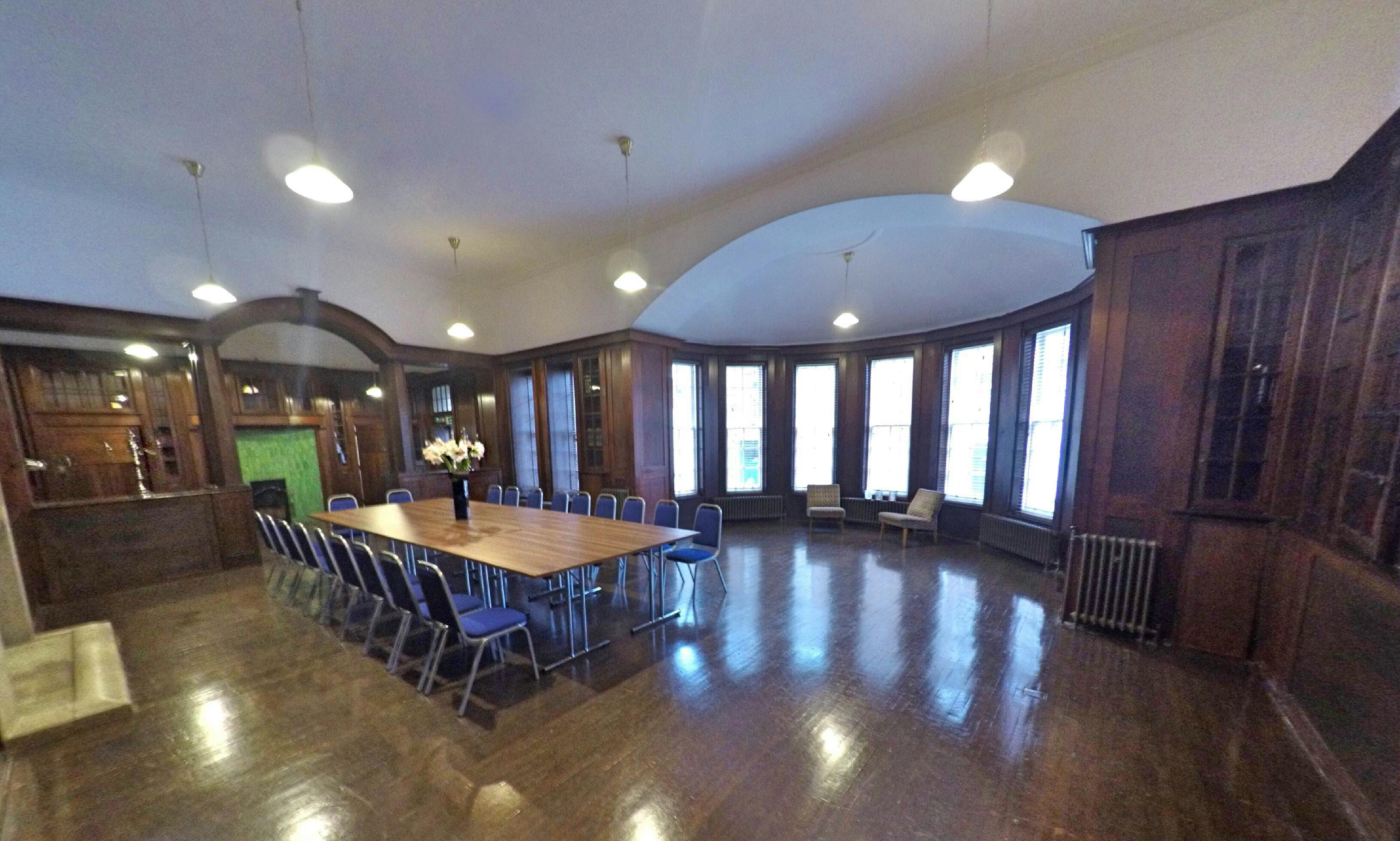 Dickens Library meeting room with large wooden table, ideal for events and discussions.