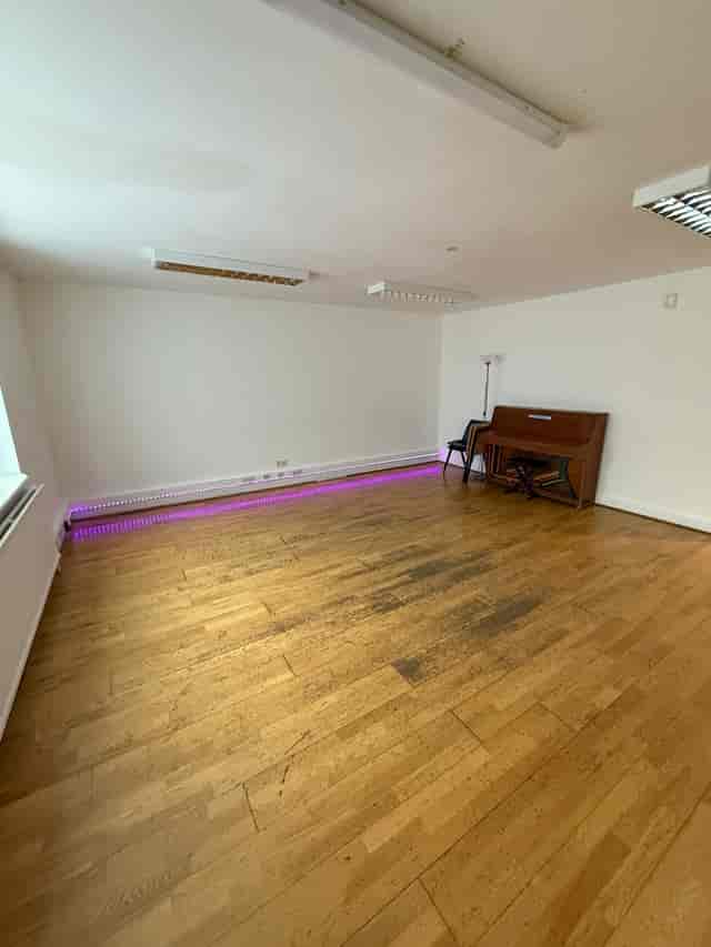 Versatile event space in artsHouse with wooden flooring and piano for gatherings.