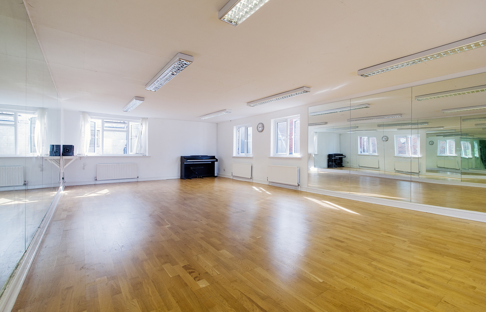 Versatile event space with polished wooden floor and natural light for workshops or dance classes. - Banner