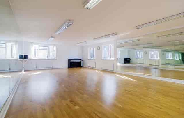 Versatile event space with polished wooden floor and natural light for workshops or dance classes.