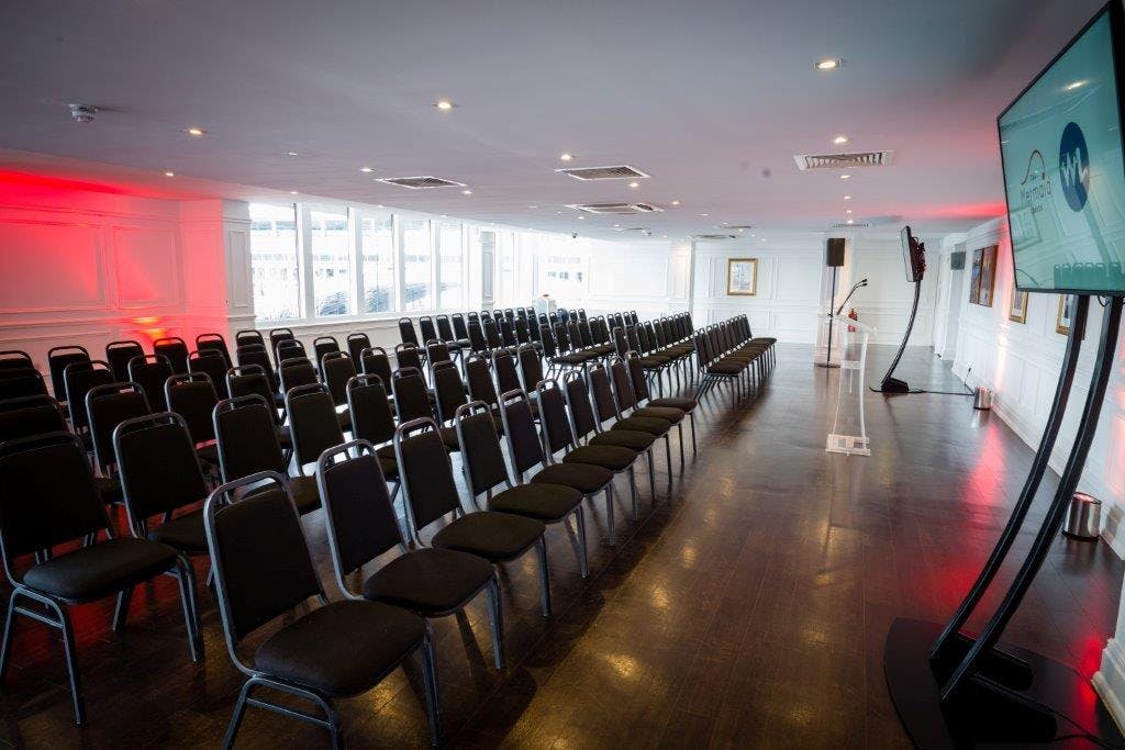 Lower River Room at The Mermaid London, modern event space with black chairs for presentations.