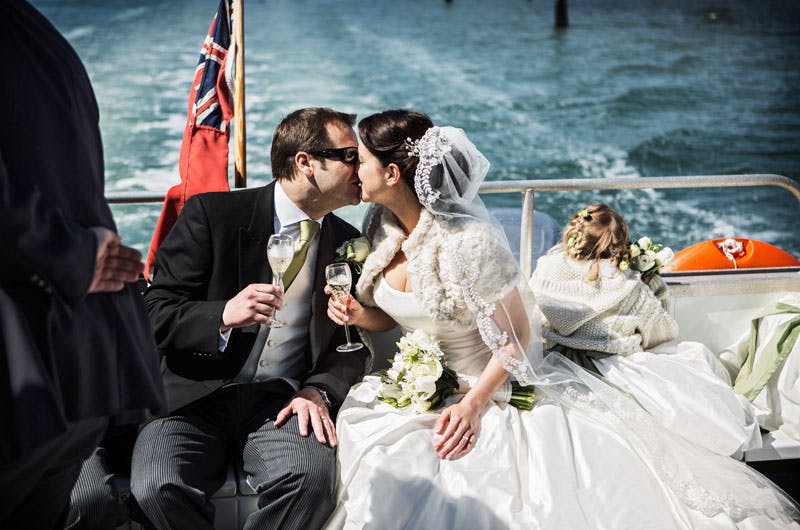 Couple celebrating wedding on boat at Spitbank Fort, showcasing romance and elegance.