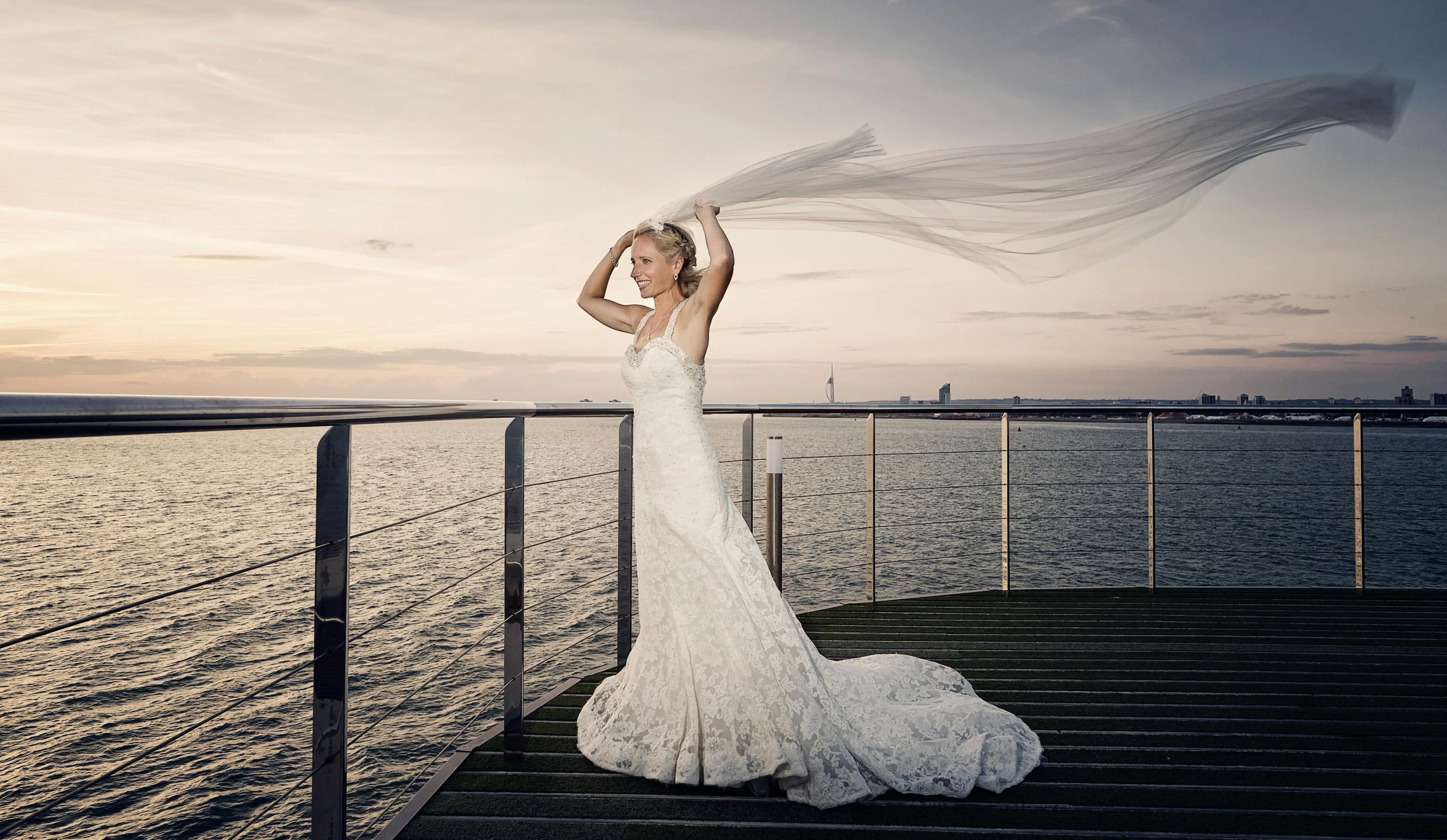 Bride in flowing veil on waterfront deck at The Victory Bar, perfect for romantic weddings.