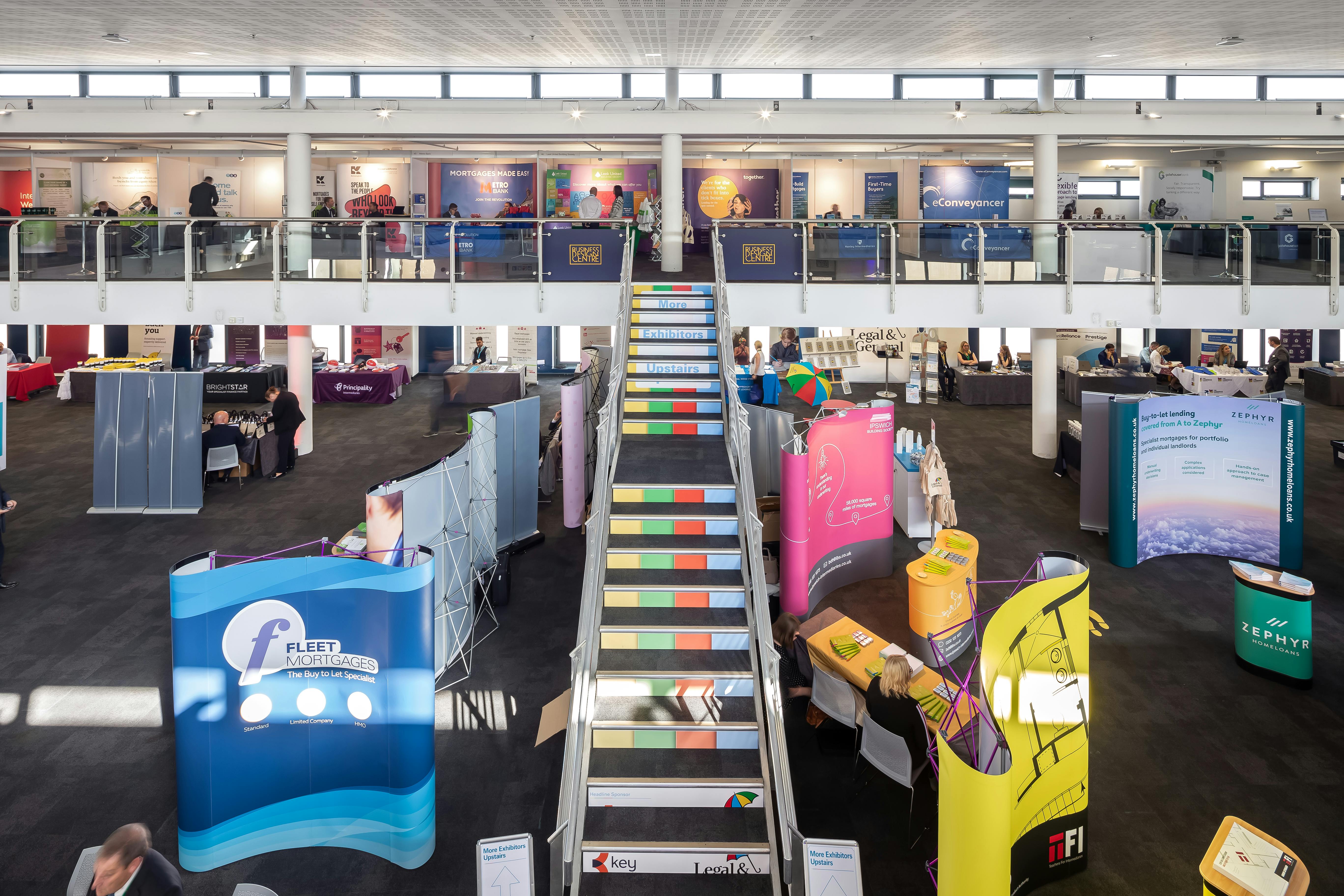 Vibrant Business Design Centre atrium with colorful booths for conferences and trade shows.