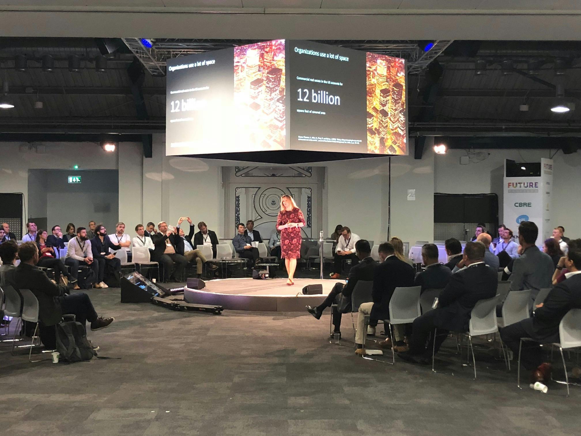 Auditorium at Business Design Centre with speaker engaging audience in a conference setting.