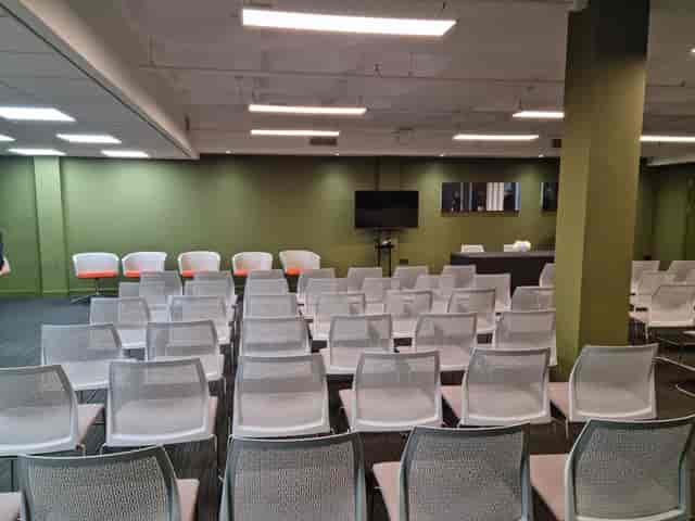 Versatile event space with white chairs and green walls for presentations and workshops.