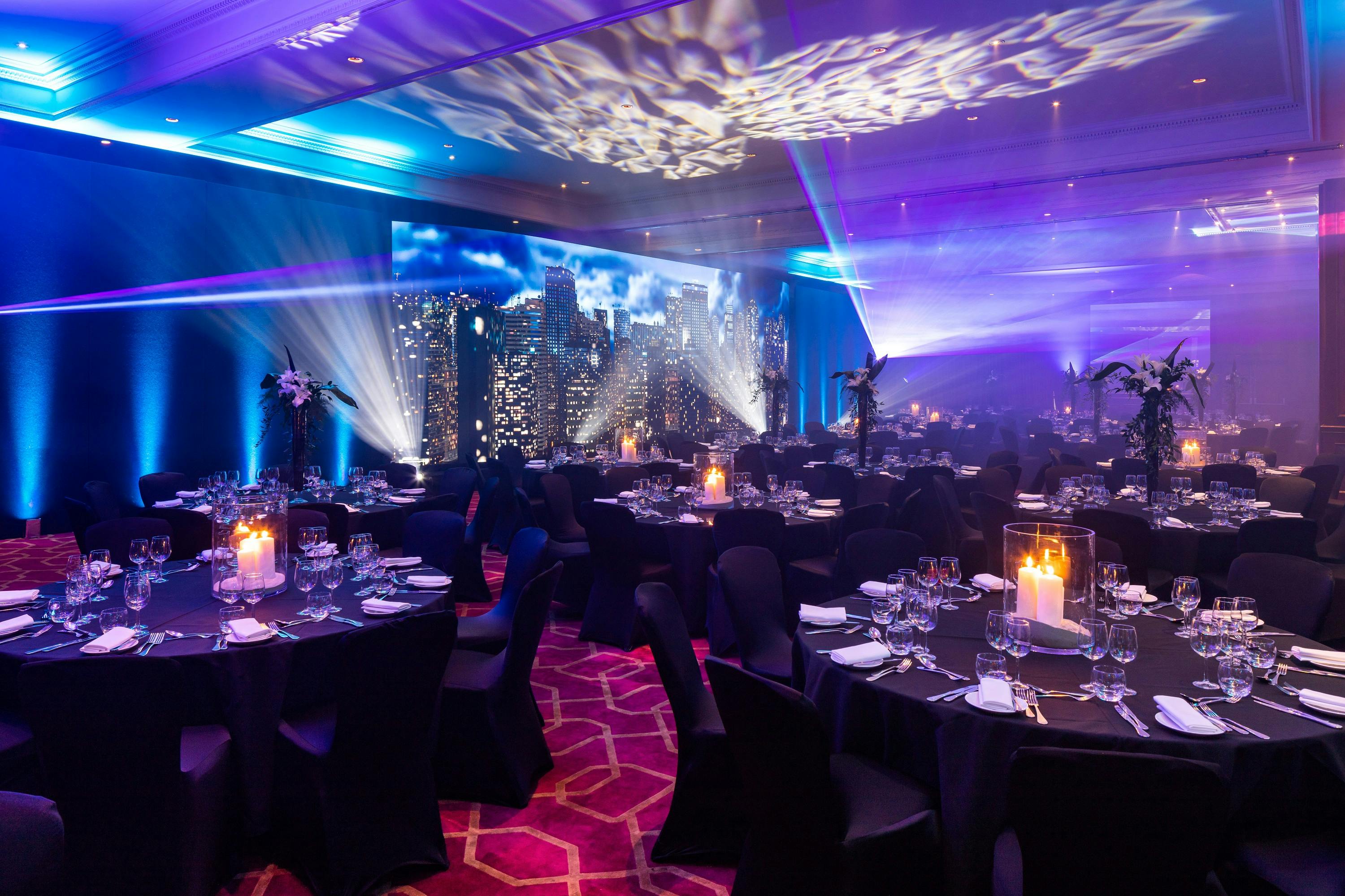 Commonwealth Suite at Radisson Blu: elegant dinner setup with city skyline backdrop.