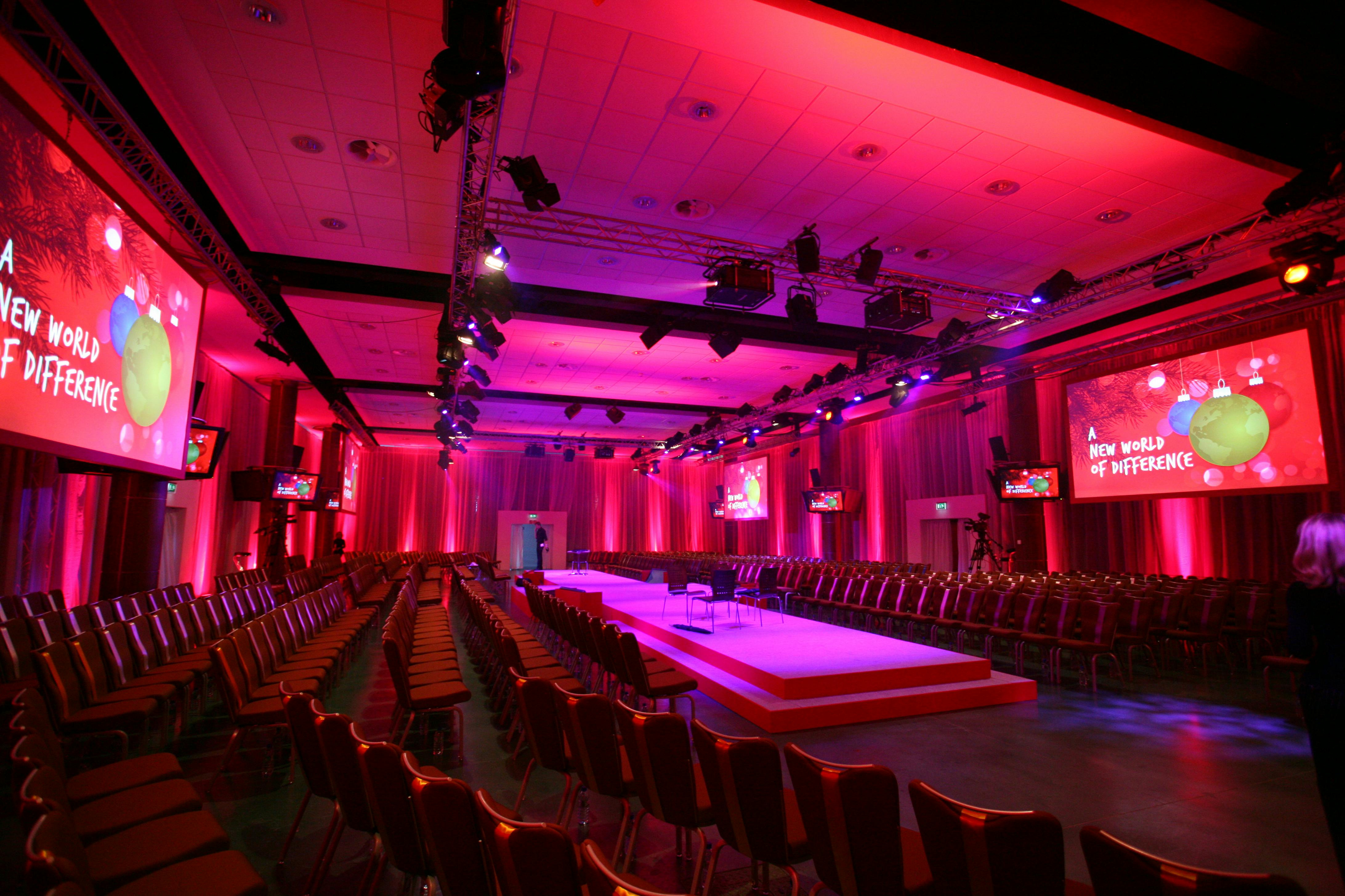 Oaks Hall at Epsom Downs: vibrant event space with stage for conferences and presentations.